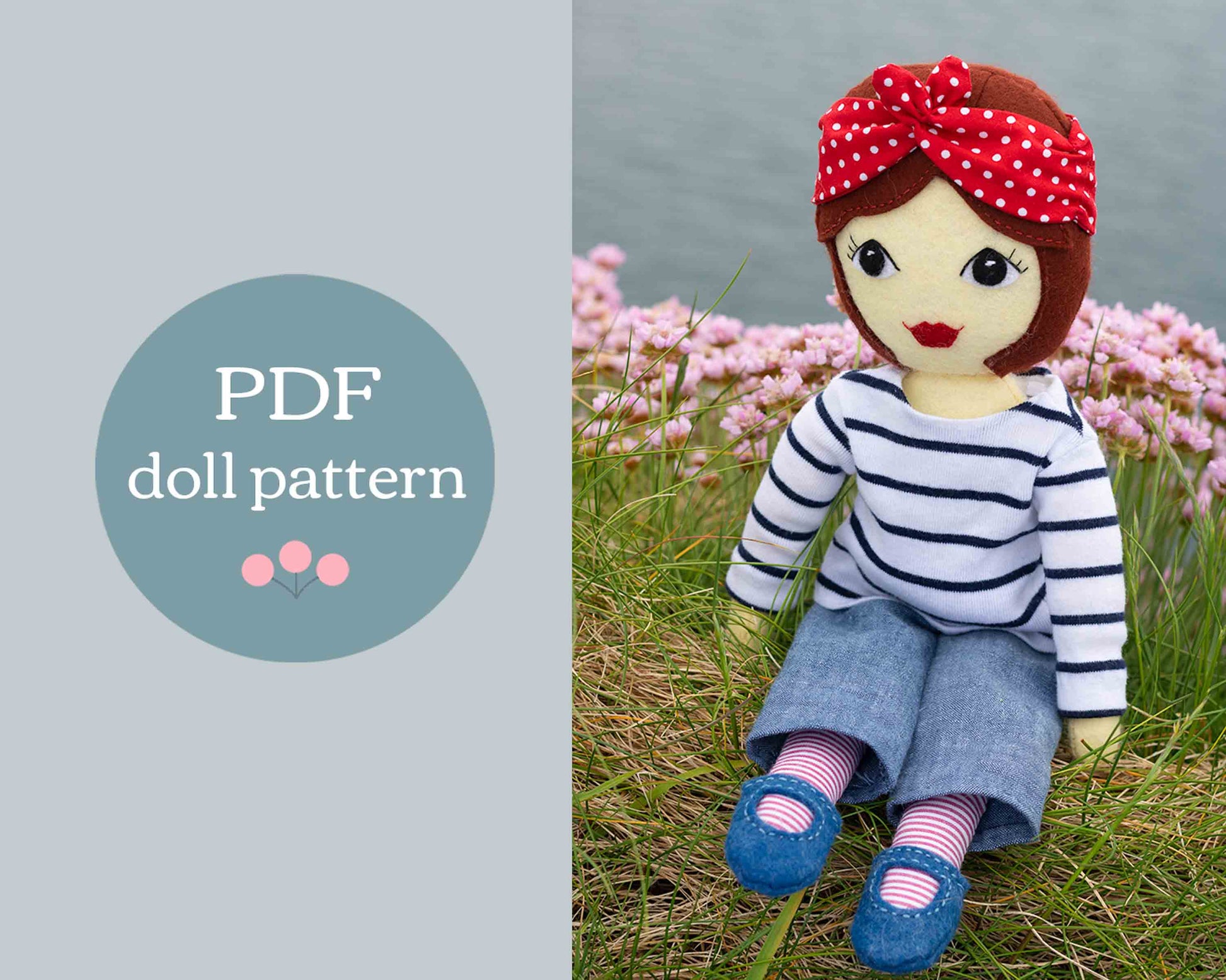 Tilly has red-brown felt hair in a bob style, large eyes with lashes and a red mouth. She wears a white top with navy blue stripes, denim pants, blue Mary Jane shoes with stripe socks and a red and white polka dot bandana head scarf. She sits on a grassy clifftop with sea pink flowers and the sea in the background.